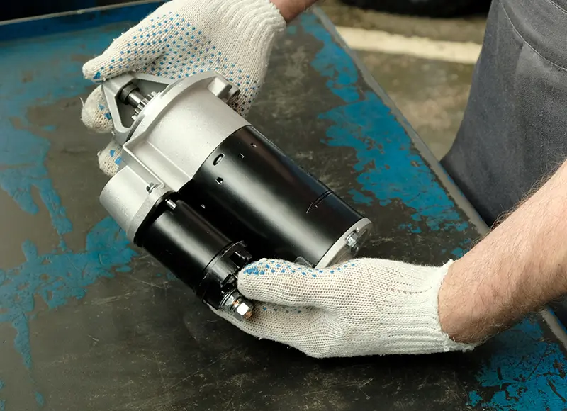 Why Certified Parts Matter - Image of vehicle starter, held in gloved hands of a mechanic